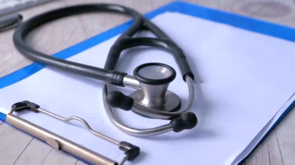 close up of stethoscope, paper and pen on clinic desk - Footage, Video