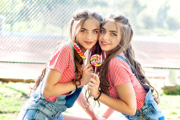 Πορτρέτο των δύο όμορφων κοριτσιών δίδυμα με γλειφιτζούρι - Φωτογραφία, εικόνα