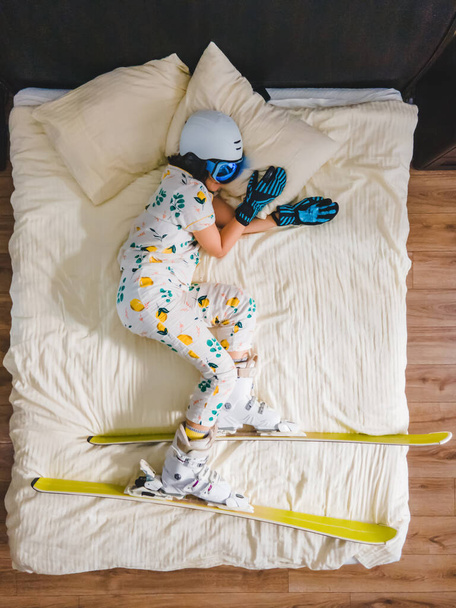 женщина в лыжном снаряжении и пижаме спит в постели, мечтая о снежных горах - Фото, изображение