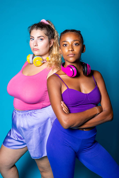 Sopiva ja ylisuuret nuoret adull poseeraa sinisellä pohjalla - Monipuolinen naiset eri kehon muotoja eristetty taustalla - itsetunto, itsetunto, kehon positiivinen käsite - Valokuva, kuva