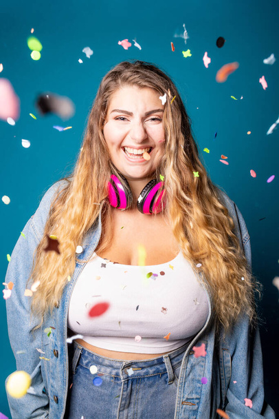 Caucasian female dancing having fun spreading confetti on  blue background - Isolated chubby young woman celebrating studio shot - celebrating, enthusiast, cheerful concept - Photo, Image