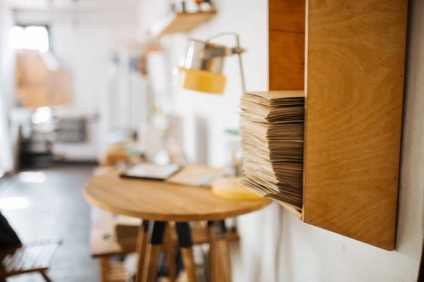 Wooden shelf with stack of craft envelopes - 写真・画像