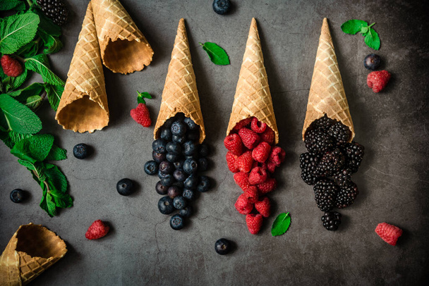 Fresh berries in waffle cones on dark stone background, top view. Concept healthy food and desert. - Foto, Imagen