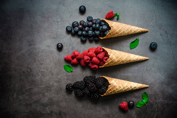 Fresh berries in waffle cones on dark stone background, top view. Concept healthy food and desert. - Fotoğraf, Görsel