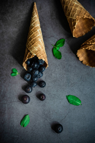 Blueberries in waffle cones on dark stone background, top view. Concept healthy food and desert. - Foto, immagini