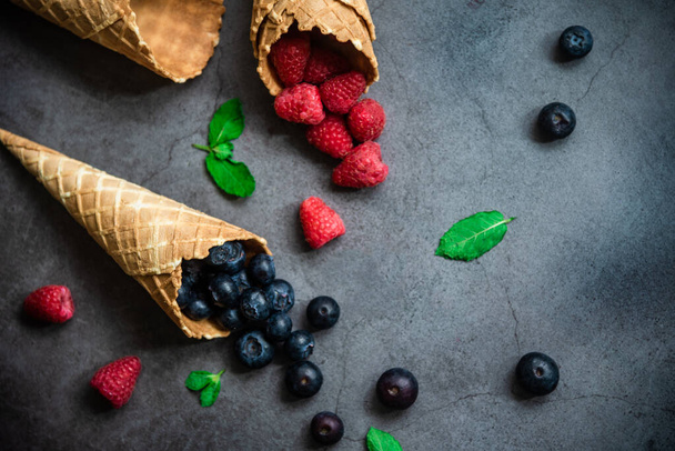 Fresh berries in waffle cones on dark stone background, top view. Concept healthy food and desert. - Foto, afbeelding