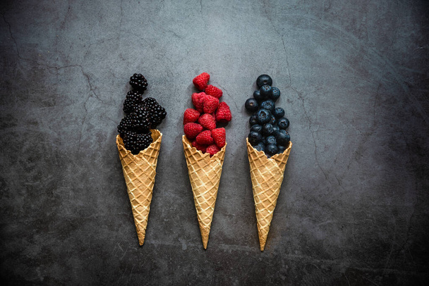 Fresh berries in waffle cones on dark stone background, top view. Concept healthy food and desert. Copy space. - Fotografie, Obrázek