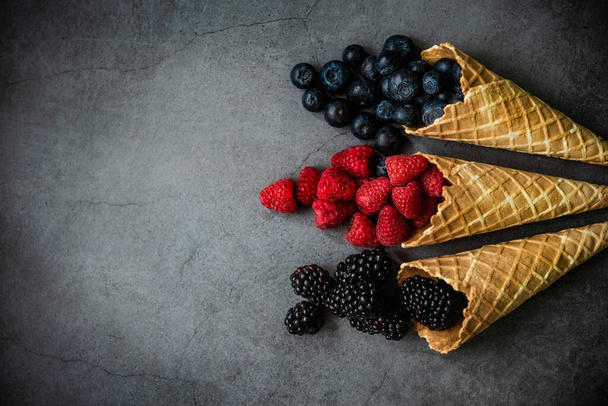 Fresh berries in waffle cones on dark stone background, top view. Concept healthy food and desert. Copy space. - Foto, immagini