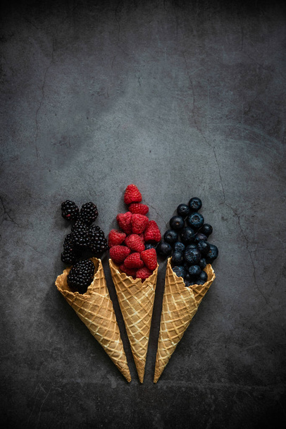 Fresh berries in waffle cones on dark stone background, top view. Concept healthy food and desert. Copy space. - Foto, Imagen