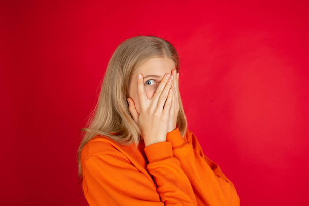 Portrait of young caucasian woman with bright emotions isolated on red studio background - 写真・画像