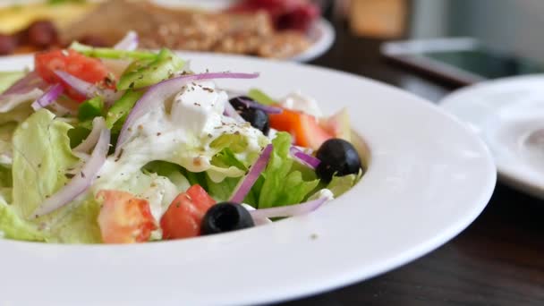 Sluiten van Griekse salade in een kom op tafel. - Video