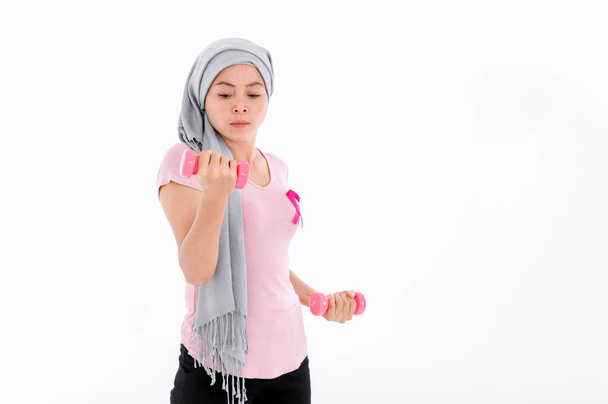 Aasialaiset naiset muslimi uskonnolliset naiset hijabissa liittää vaaleanpunainen nauha niiden toppeja. Harjoitus nostamalla vaaleanpunaisia käsipainoja. rintasyövän käsite, syövän ehkäisy käsite. Akne ja tummat pilkut. - Valokuva, kuva