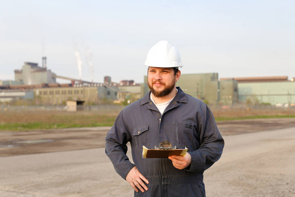 Portret inżyniera stojącego na placu budowy i trzymającego dokumenty. - Zdjęcie, obraz