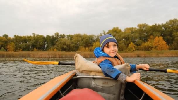 Avond kajak tocht langs de rivier in de herfst. De actieve levensstijl van het kind in het gezin. - Video