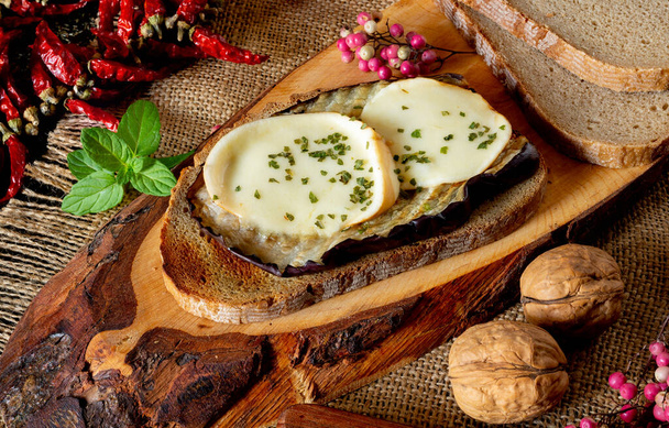 запечені скибочки баклажанів з сиром на скибочці хліба з цільнозерновим борошном, оливковою олією та петрушкою та диким перцем
 - Фото, зображення