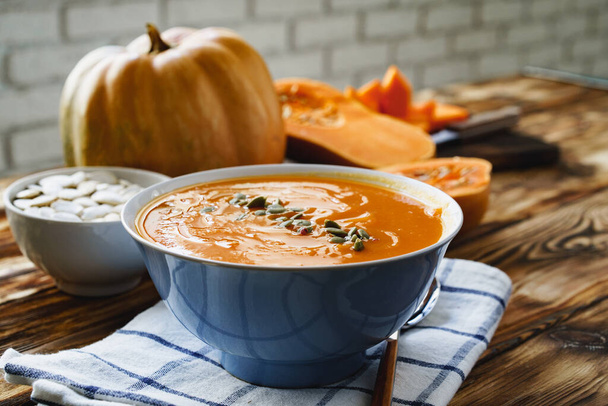 Creamy pumpkin soup on a wooden table - Фото, изображение