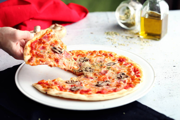 Ruka uchopí kousek celé pizzy. Dekorace s barvami vlajky Itálie - Fotografie, Obrázek