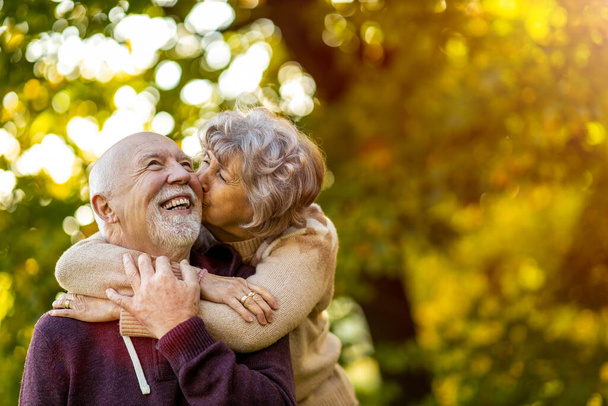 Счастливая старшая пара проводит время вместе в красивом городском парке осенью - Фото, изображение