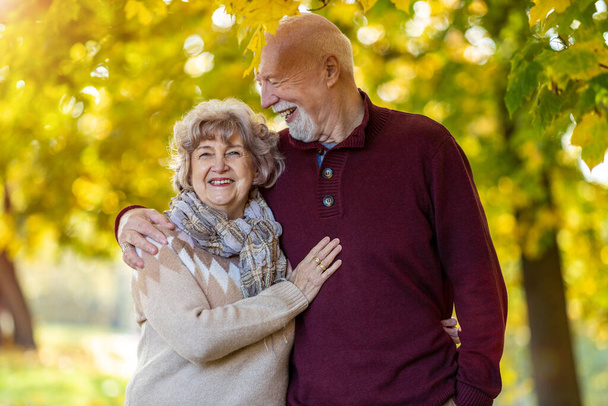 Счастливая старшая пара проводит время вместе в красивом городском парке осенью - Фото, изображение