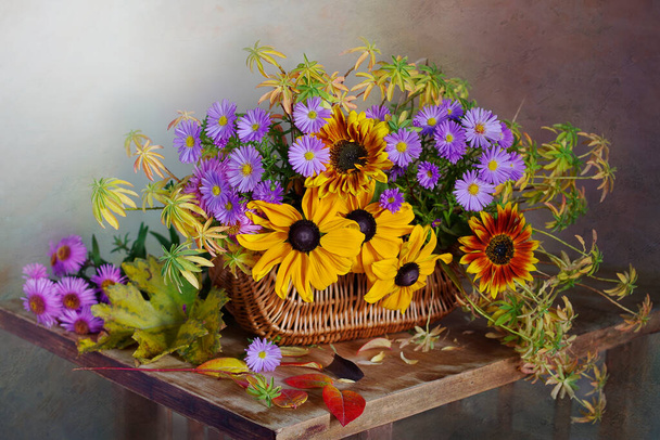 Beautiful bouquet of autumn flowers in a basket on the table. - Fotografie, Obrázek