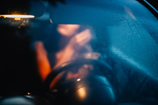 Unfocused young woman puts on makeup inside a car at sunset - Valokuva, kuva