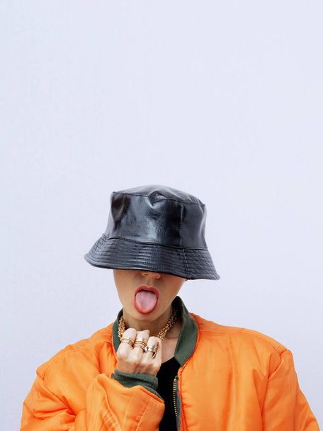 Playful Girl in fashion urban street outfit. Trendy orange bomber jacket and stylish black bucket hat. Fall winter seasons lookbook. Style in details - Foto, Imagen