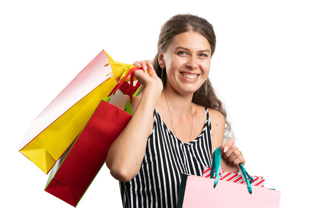 Veselá žena dospělý model na sobě moderní ležérní letní oblečení nesoucí barevné tašky po nákupním řádění jako konzumní koncept izolované na bílém pozadí studia - Fotografie, Obrázek