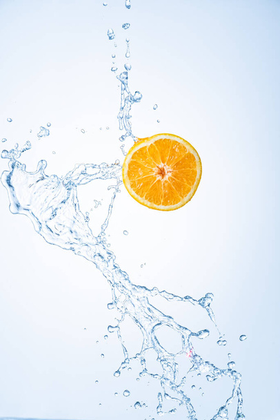 Половина апельсинових фруктів з бризками води в повітрі, ізольовані на світло-блакитному фоні
 - Фото, зображення