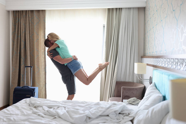 Man lifted smiling woman in his arms in bedroom near window - 写真・画像