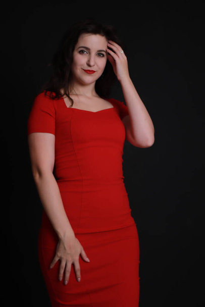 sexy attractive brunette in red skinny dress isolated on black background. studio shoot. emotional actress.  - 写真・画像