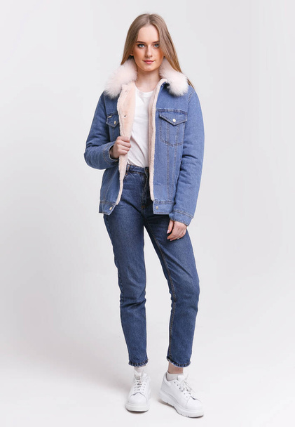 Young Woman in a denim suit with a fur collar on a white background. Clothing advertising concept. - 写真・画像