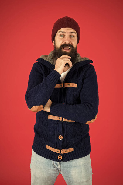 Warm and comfortable. Fashion menswear shop. Masculine clothes concept. Winter menswear. Clothes design. Man bearded warm jumper and hat red background. Winter season menswear. Personal stylist - Foto, immagini