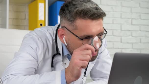 Orvos néz nagyító üveg, diagnosztizálja beteg online video hívás laptop webkamera - Felvétel, videó