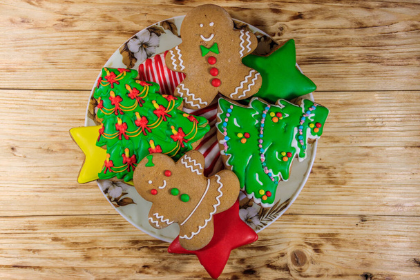 Talerz ze smacznymi świątecznymi ciasteczkami z piernika w kształcie choinki, piernika, gwiazdki i świątecznej pończochy na drewnianym stole. Widok z góry - Zdjęcie, obraz
