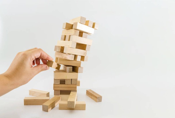 Torre de bloques de madera y manos humanas toman un bloque. planificación, riesgo y estrategia en los negocios. a riesgo de tomar un bloque de madera de la torre. - Foto, Imagen