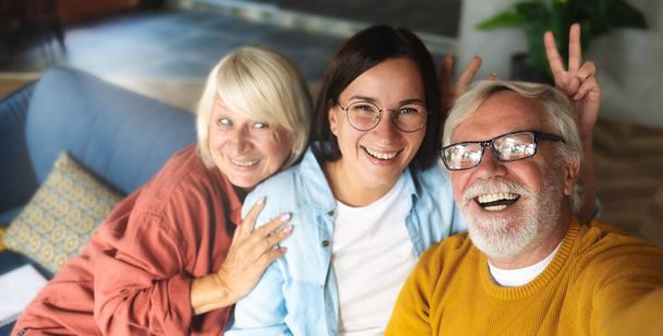 Happy elderly people with granddaughter having fun on the couch and chatting on a video call - Foto, Imagen