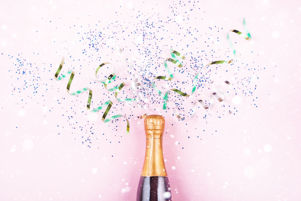 Szilveszteri szerpentin repül ki az üveg pezsgő, sokszínű flitterek egy könnyű háttér. 2021 újévi tartalma. Lapos fektetés - Fotó, kép