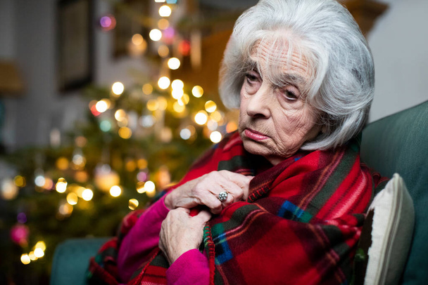 Sad And Lonely Senior Woman Unhappy About Spending Christmas At Home Alone Wrapped In Blanket - Photo, Image