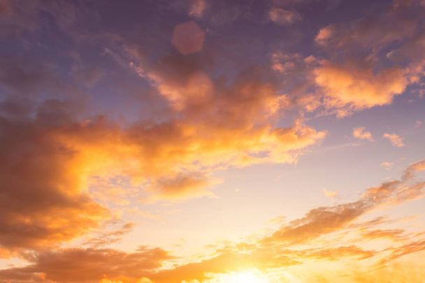 Kleurrijke oranje-paarse dramatische wolken verlicht door de ondergaande zon tegen de avondzonsondergang hemel. Wolkenlandschap. - Foto, afbeelding