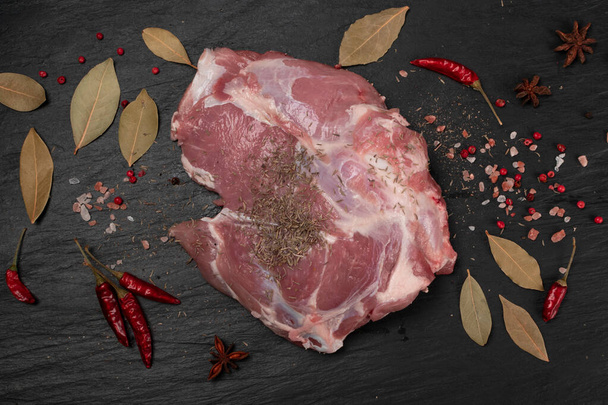 黒石板の背景に挽いた黒胡椒とスパイスで新鮮な生肉の肩肉。羊の切り身やフィレ-トップビューの大規模な作品 - 写真・画像