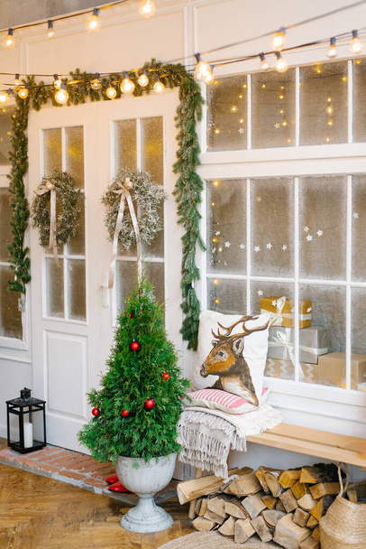 Vstupní dveře do domu, zdobené na Vánoce a Nový rok. Stromy ve vázách a vánoční věnce na bílých dveřích - Fotografie, Obrázek