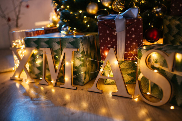 New Year 2021 interior with candles, bulbs and bokeh. Room decorated to christmas celebration. Christmas tree with presents - Photo, image