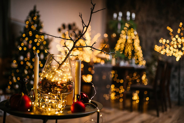New Year 2021 interior with candles, bulbs and bokeh. Room decorated to christmas celebration. Christmas tree with presents - Foto, Imagen