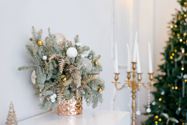 Christmas decor in a classic living room or Spruce branches in gold vases with toys and a gold candlestick on the dresser - Zdjęcie, obraz