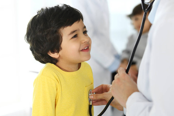 Lekarz badający pacjenta za pomocą stetoskopu. Słodki arabski chłopiec na wizycie u lekarza. Koncepcja medycyny i opieki zdrowotnej - Zdjęcie, obraz