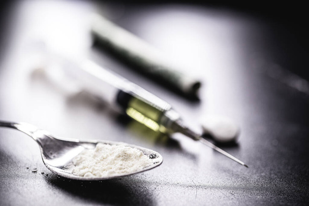 dope, narcotics, illegal drugs on dark black background. Heroin syringe, pills, cocaine. - Photo, Image