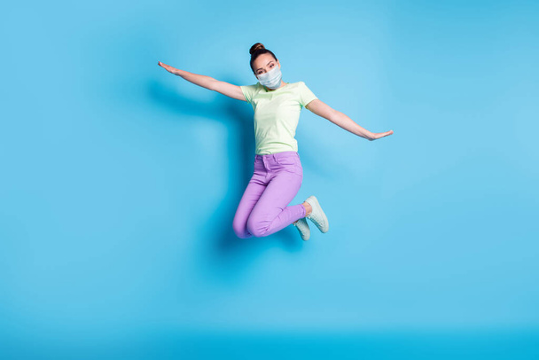 Full length photo of young girl jumping high keeping hands like plane wear mask isolated on vibrant blue color background - Φωτογραφία, εικόνα