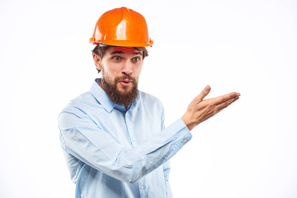 オレンジのヘルメットシャツの建設業界の男は軽い背景で働いていた - 写真・画像