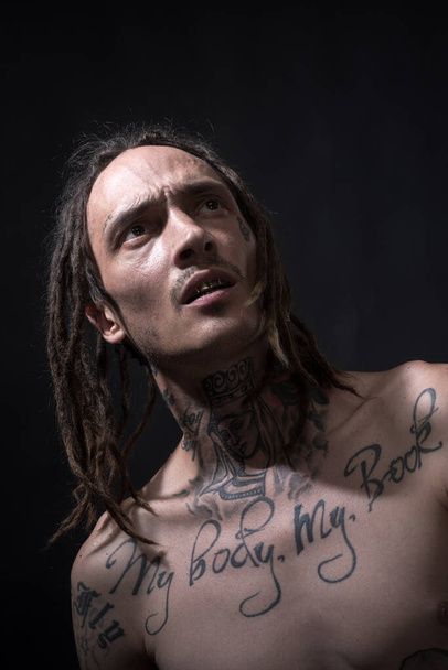 Young hipster with tattoo. Portrait of modern guy with dreadlocks. - Foto, afbeelding