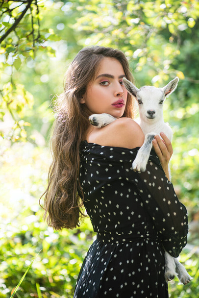 Natural young woman. Virgin girl in village hold yeanling. Sprinf fashion portrait of beautiful woman holding a small lamb. - Φωτογραφία, εικόνα